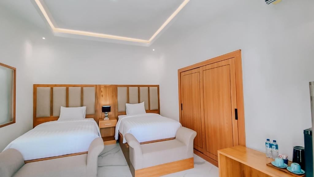 a hotel room with two beds and a desk at Rejuvenate Resort and Restaurant in Jembrana