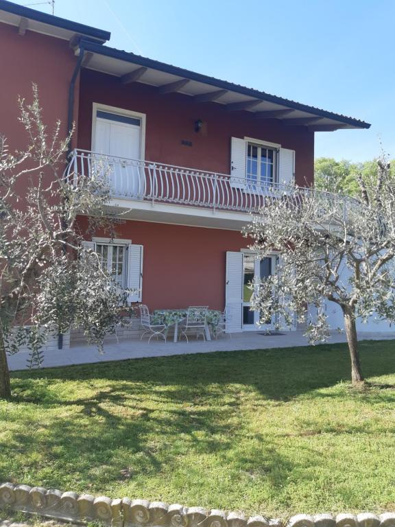 une maison rouge avec des fenêtres blanches et une cour dans l'établissement Pace, Luminosità e Comodità a due passi dal Garda, à Volta Mantovana