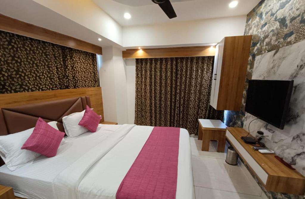 ein Schlafzimmer mit einem großen Bett und einem TV an der Wand in der Unterkunft Hotel RK ICON in Ahmedabad