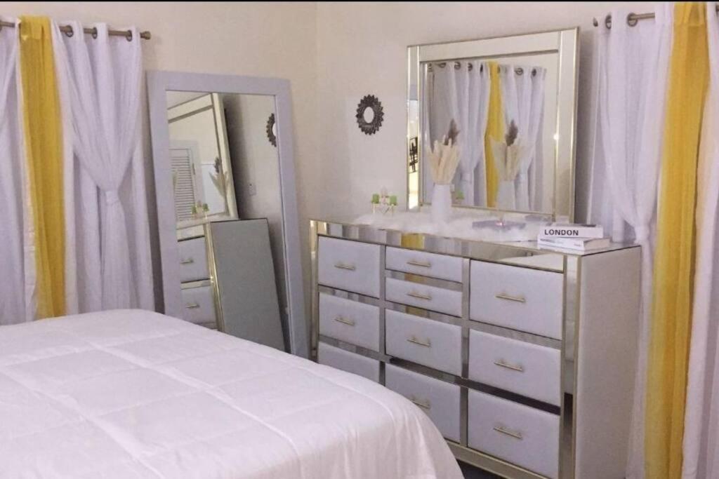 a bedroom with a white dresser and a mirror at Welcome to Barefoot Bliss Short Term Rental 