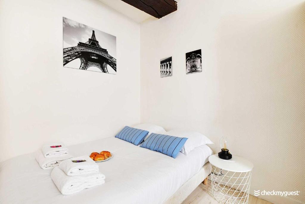 - une chambre blanche avec un lit, des serviettes et la tour Eiffel dans l'établissement Cosy studio le Marais, à Paris