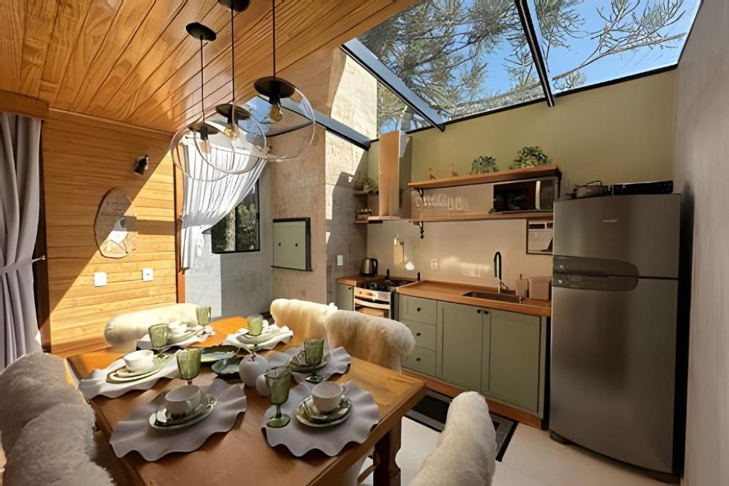 una cucina e una sala da pranzo con tavolo e frigorifero di Chalé O Canto da Araponga a Águas Brancas