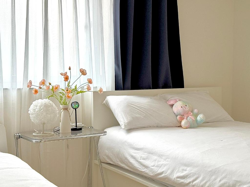 a white bed with a stuffed animal on a pillow at 사당 그린나래 스테이 in Seoul