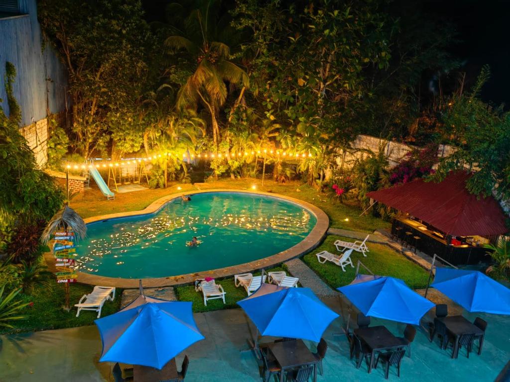 una vista aérea de una piscina por la noche con sombrillas azules en Chanchamayo Inn Hotel, en La Merced