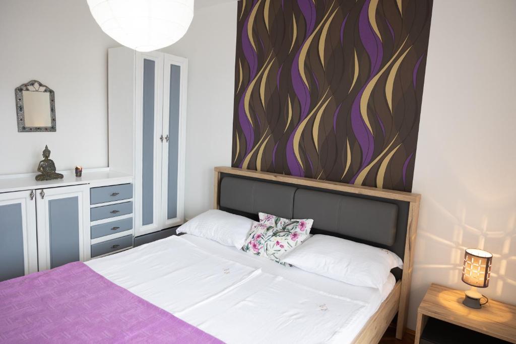 a bedroom with a bed with a purple accent wall at Apartmani Novkovic in Bar