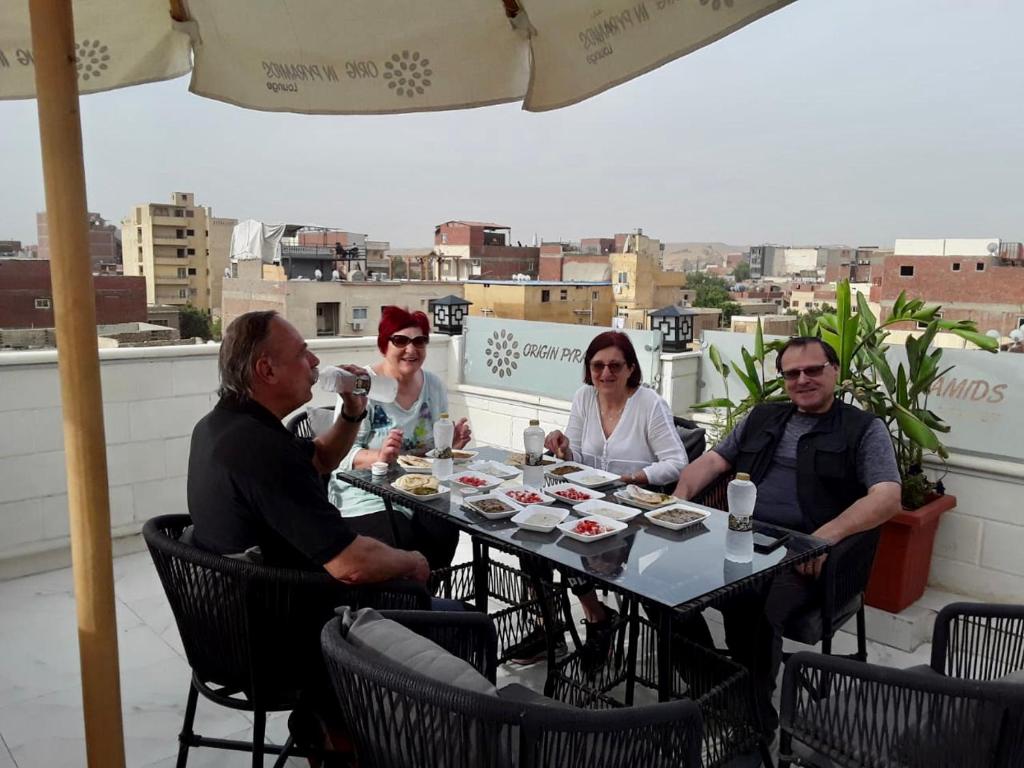 Aurora Pyramids Hotel في القاهرة: مجموعة من الناس يجلسون حول طاولة على السطح