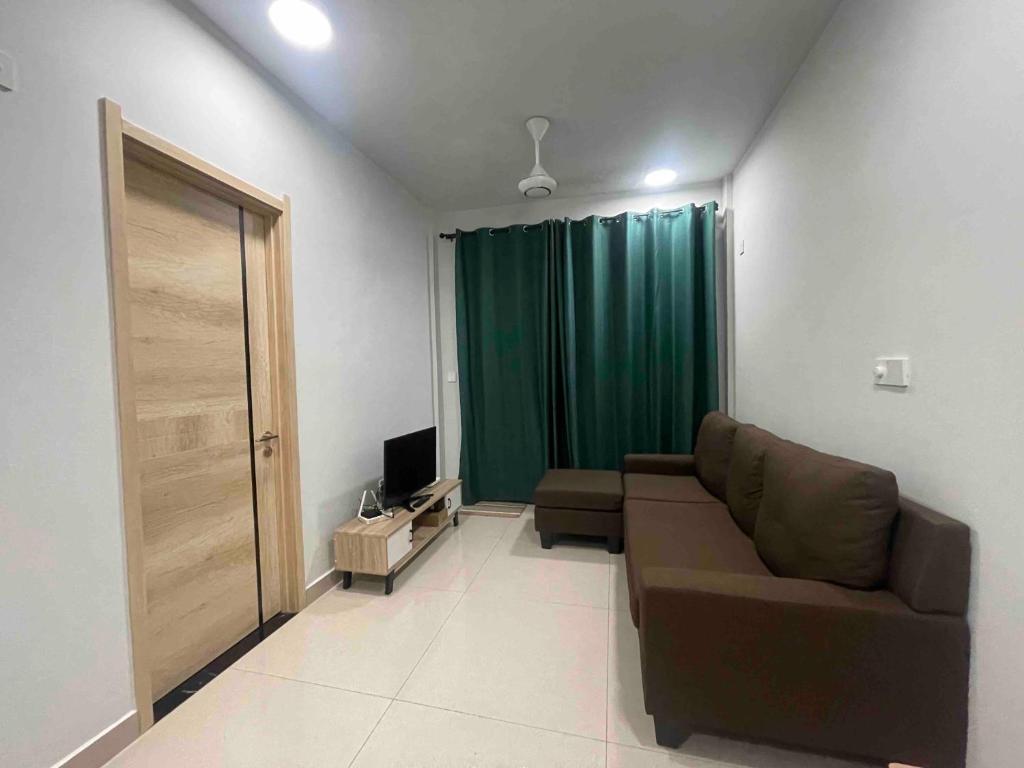 a living room with a couch and a green curtain at Cozy One-Room Apartment Stay in Hulhumale