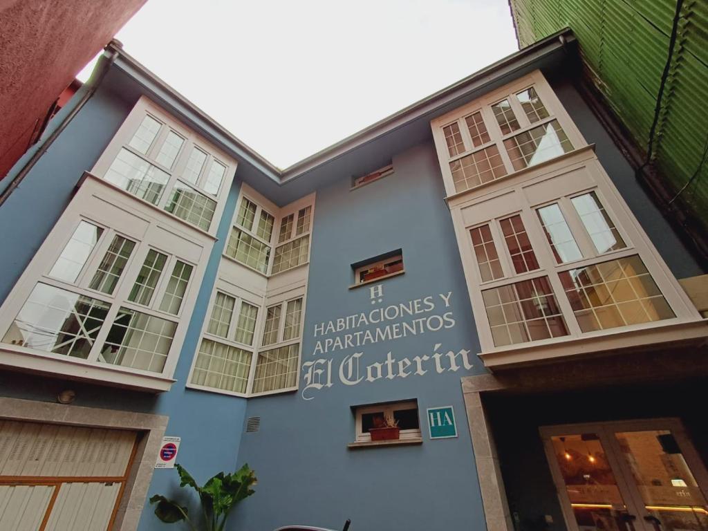 un bâtiment bleu avec des fenêtres et un panneau sur celui-ci dans l'établissement Hotel El Coterin Apartamentos y Habitaciones, à Arenas de Cabrales