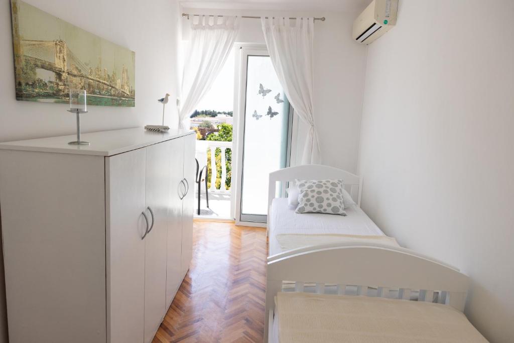 Biały pokój z łóżkiem i kuchnią w obiekcie Apartmani Novkovic w Barze