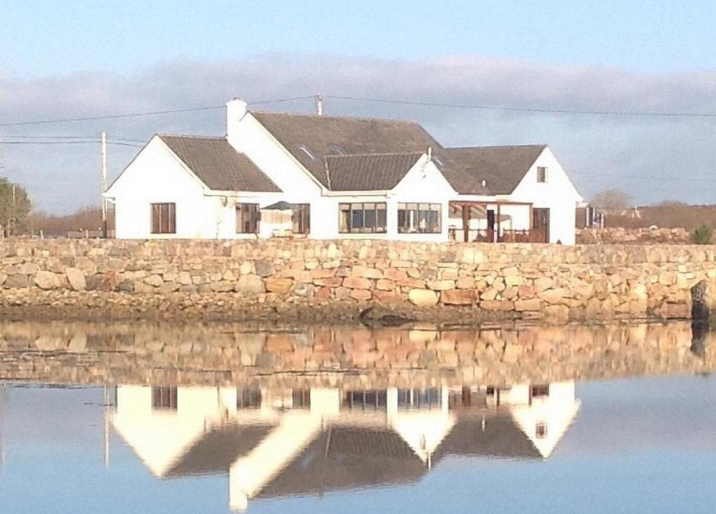 ein weißes Haus auf einer Steinmauer in der Unterkunft 4 bedroom holiday home overlooking the sea in Connemara in Rossaveel