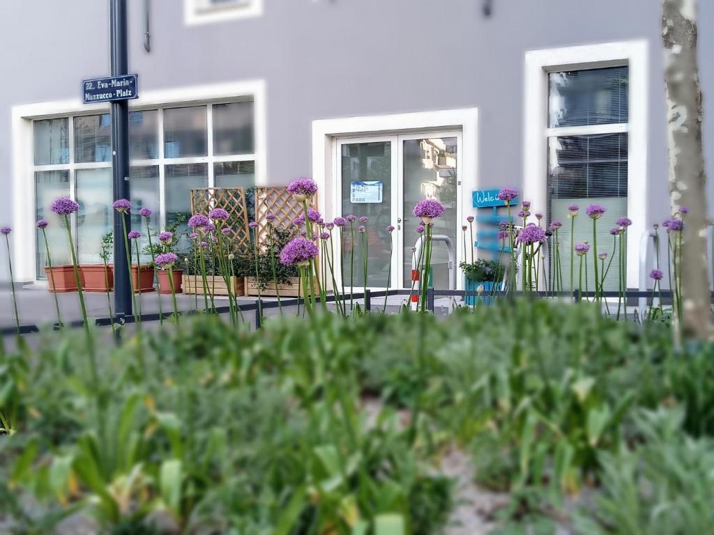 Une bande de fleurs violettes devant un bâtiment dans l'établissement Ferienzimmer Seepark, à Vienne