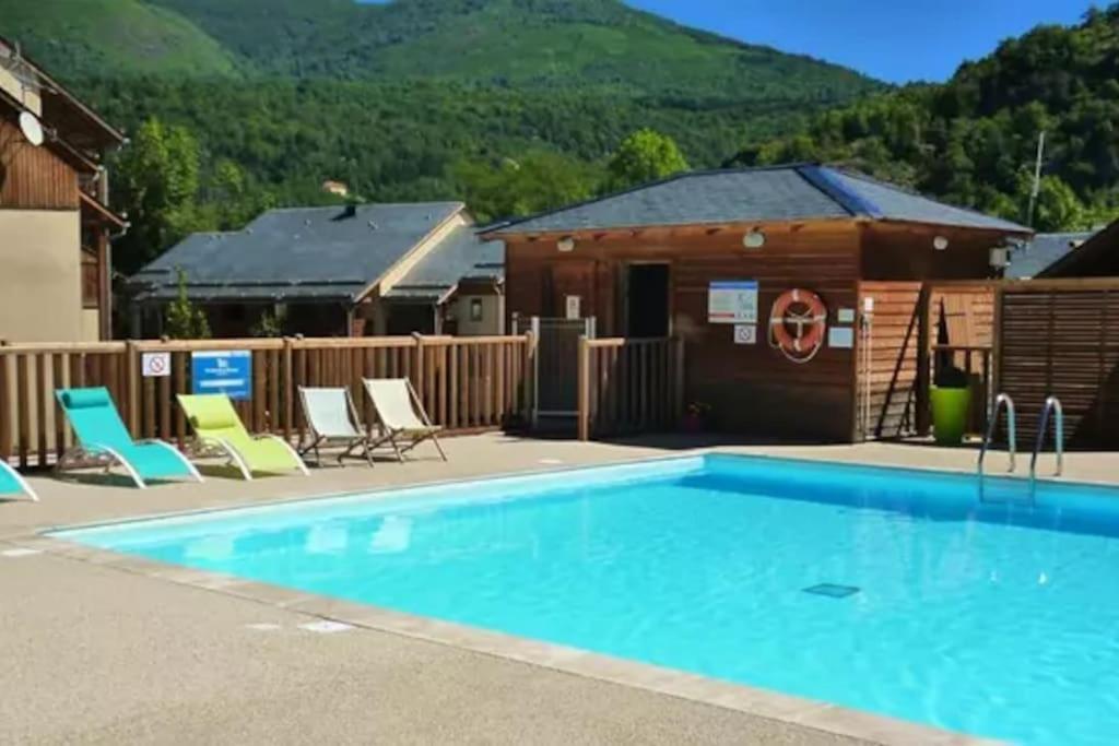 une piscine avec des chaises et un bâtiment dans l'établissement Grand studio à la montagne, à Ax-les-Thermes