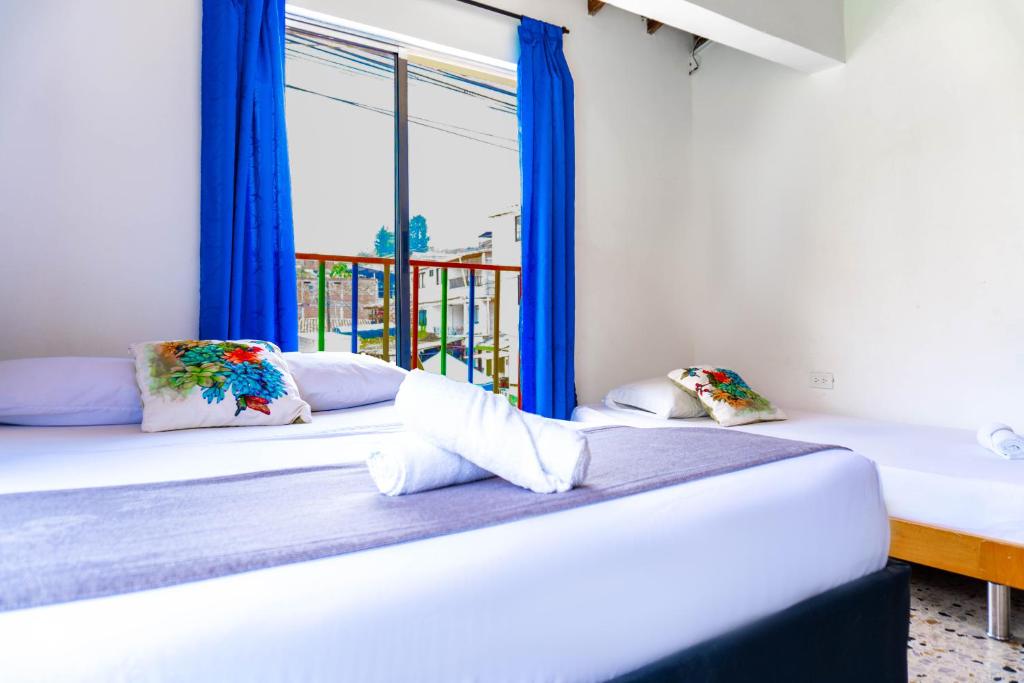 2 camas en una habitación con ventana en Hotel Villa Guatape, en Guatapé