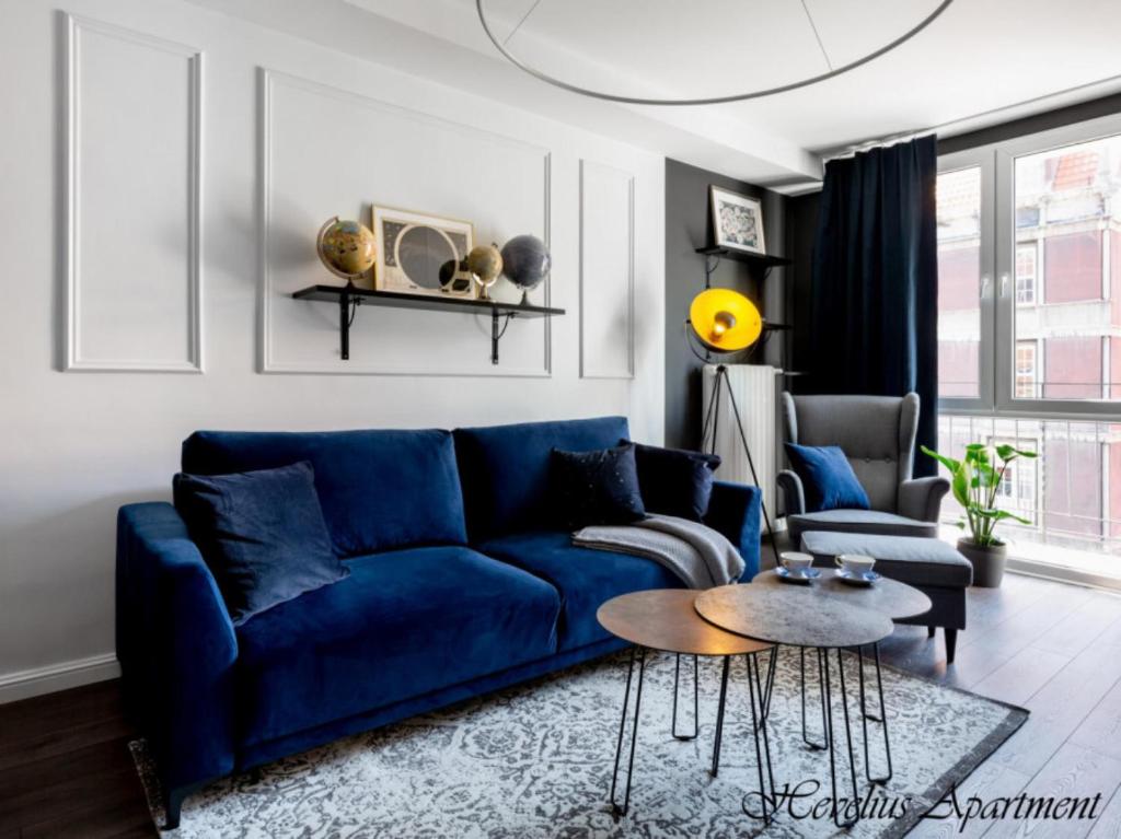 a living room with a blue couch and a table at Bayside Apartments in Gdańsk