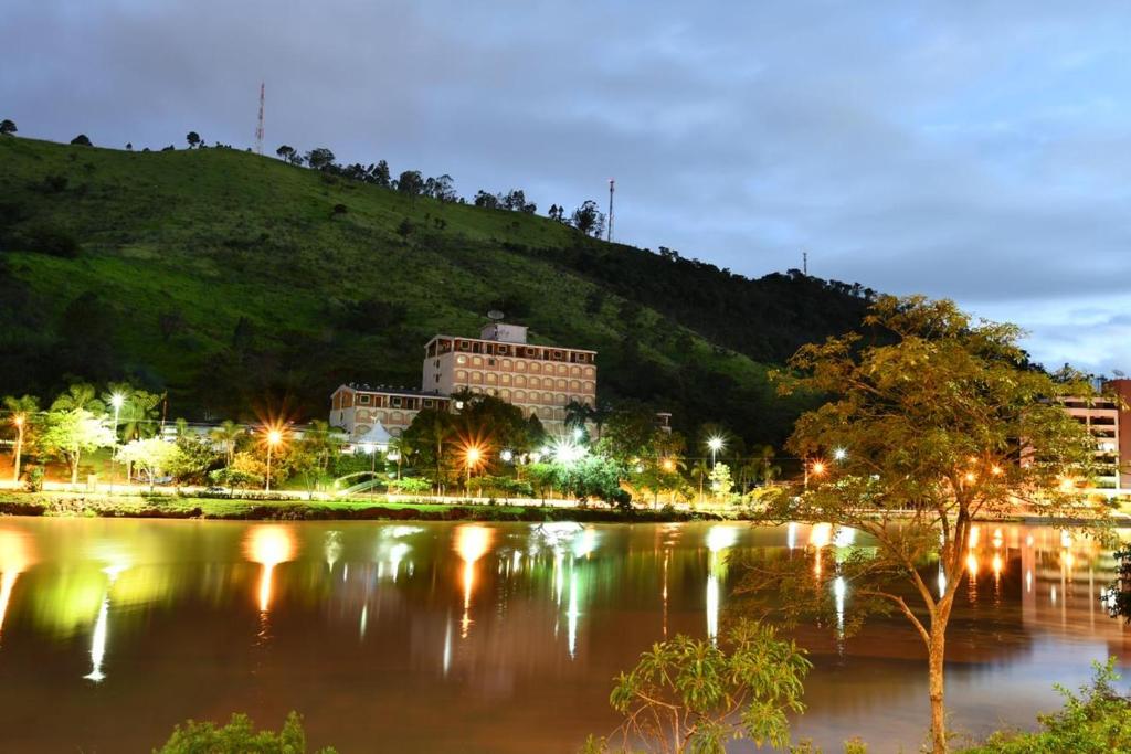 uma cidade iluminada à noite ao lado de um rio em FLATs CAVALINHO BRANCO em Águas de Lindoia