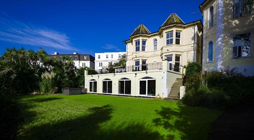 a large white house with a green yard at Crofton House Hotel in Torquay