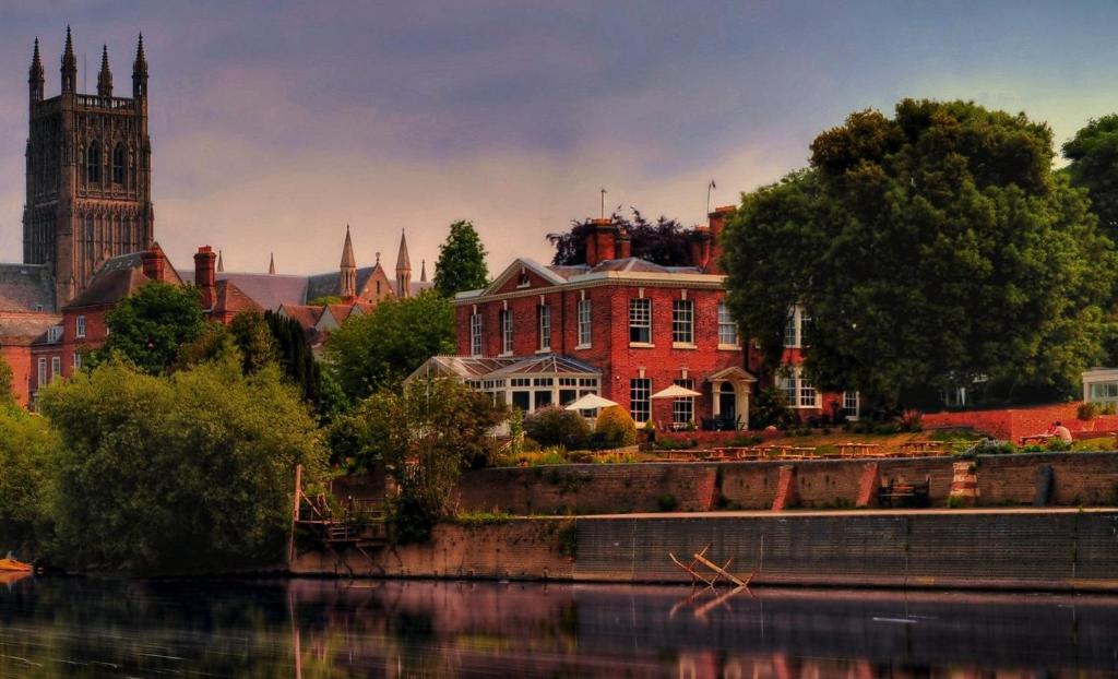 a large red brick building next to a river at Diglis House Hotel in Worcester