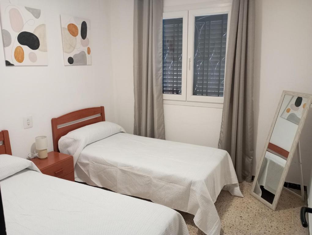 a hotel room with two beds and a mirror at Habitación en chalet cerca de la playa en Benicasim in Benicàssim