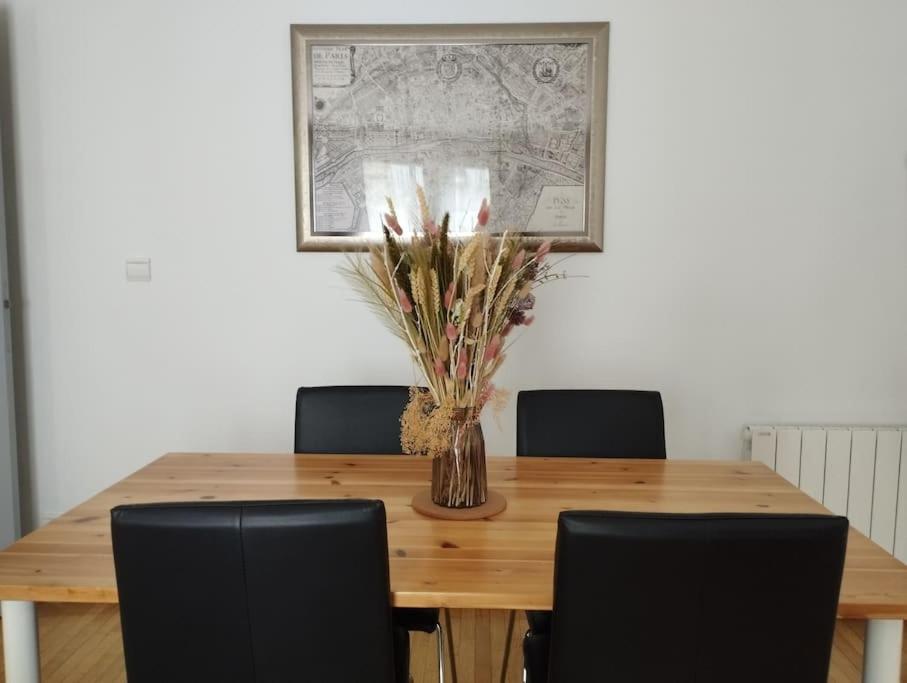 a wooden table with chairs and a vase with flowers at Appartement calme proche Paris in Villiers-sur-Marne