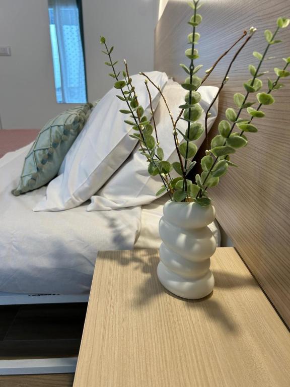 um vaso branco sentado numa mesa ao lado de uma cama em Etna sicula em San Giovanni la Punta