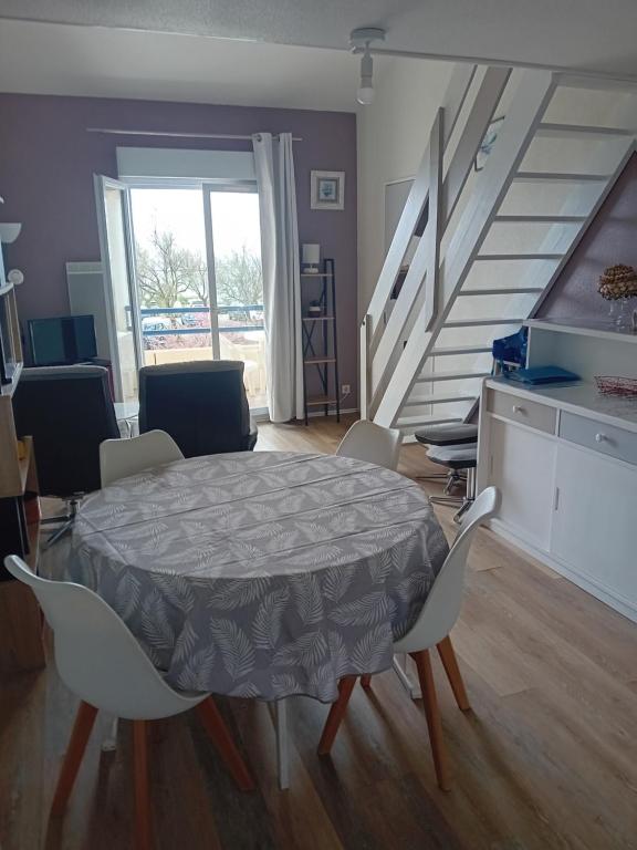 - une salle à manger avec une table, des chaises et des escaliers dans l'établissement Duplex face océan T2 + mezzanine à Bretignolles sur mer, à Bretignolles-sur-Mer