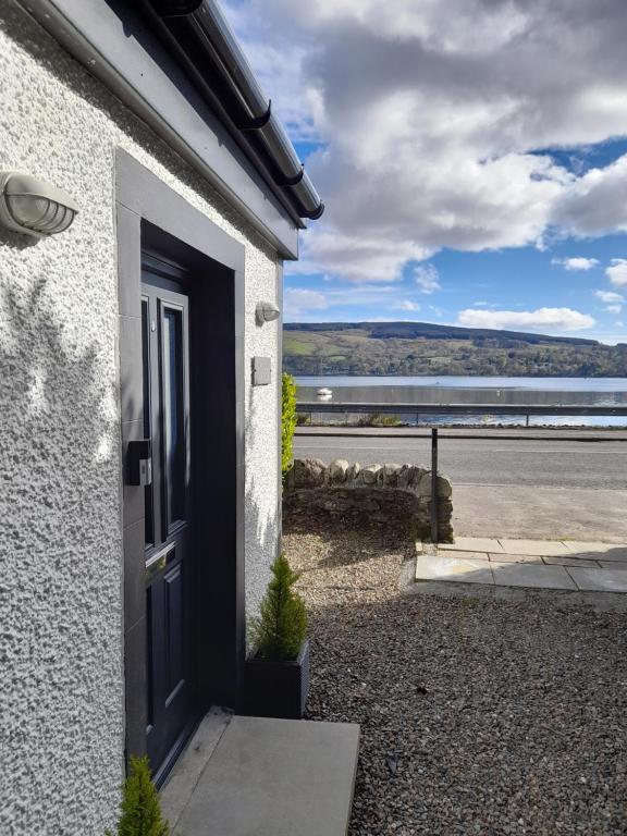 a door to a house with a view of the water at Lochside cottage with scenic terrace views, Argyll in Clynder