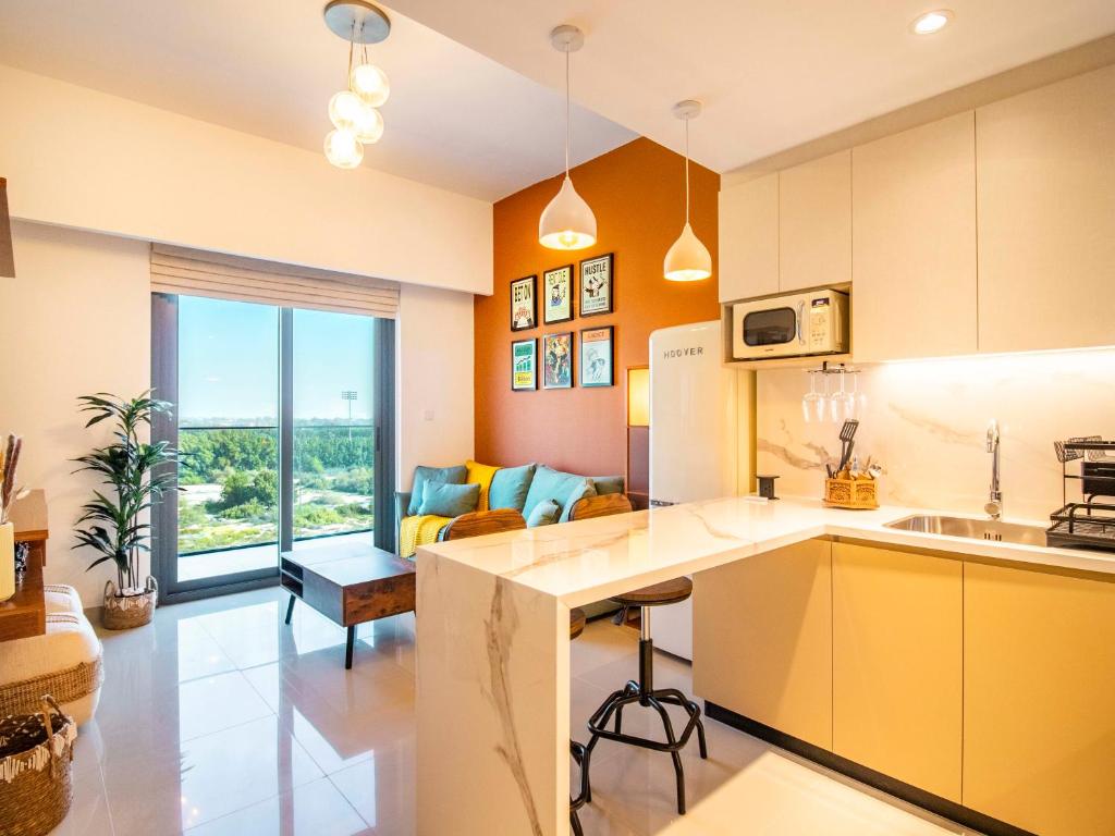 a kitchen with yellow cabinets and a living room at Luxury 1-Bedroom Hideaway In Meydan in Dubai