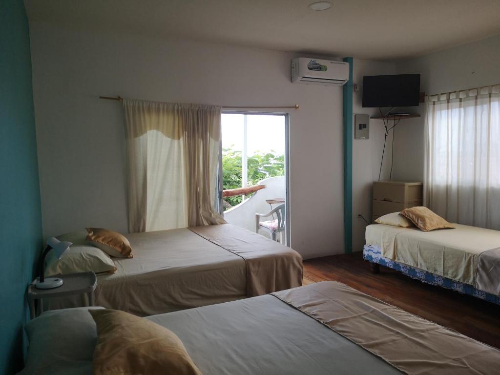Habitación de hotel con 2 camas y ventana en Hostal Cabañas Don Jorge en Puerto Baquerizo Moreno