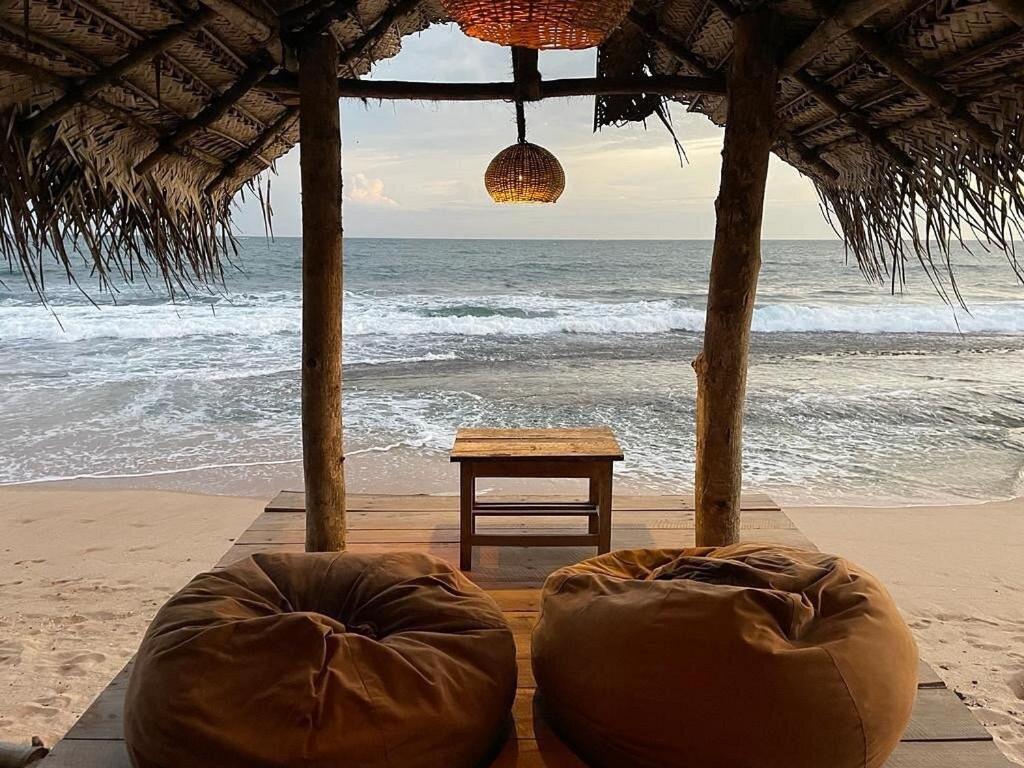 - une tente sur la plage avec une table et l'océan dans l'établissement Cinnabar Resort, à Tangalle