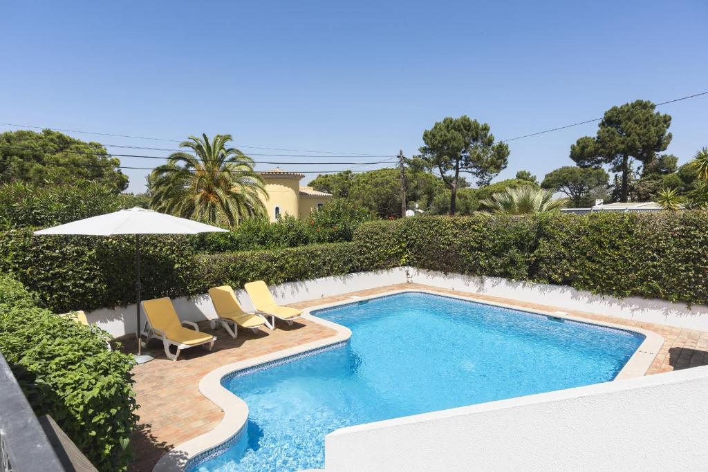 una piscina con sillas y sombrilla en Vila Norte - Private Pool by HD PROPERTIES, en Vilamoura