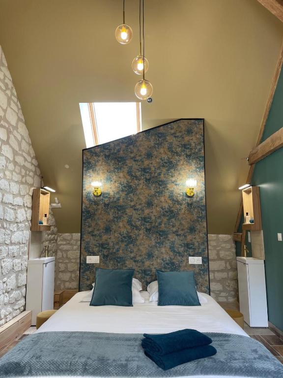 a bedroom with a large bed with blue pillows at Le Relais, La Dormance, Le Bois Dormant in Châteauvieux