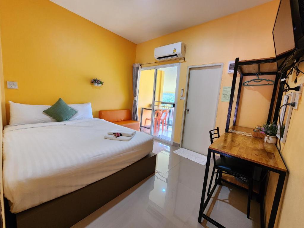um quarto com uma cama, uma secretária e uma varanda em ลิตเติ้ลโฮม ที่พักเพชรบุรี em Phetchaburi