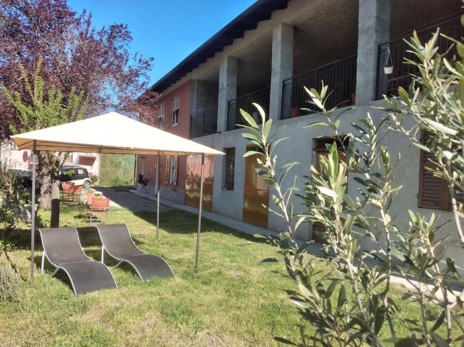 a group of chairs under an umbrella next to a building at La Casa Rossa -Dimora di campagna in Montechiaro D'acqui