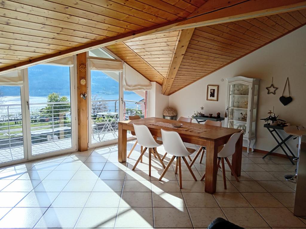 uma sala de jantar com uma mesa de madeira e cadeiras brancas em La Posada sul Colle em Tenna 