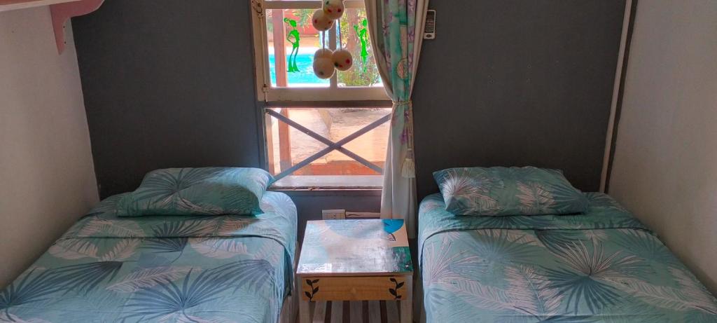 Dos camas en una habitación con ventana. en Cunumí, en Puerto Iguazú