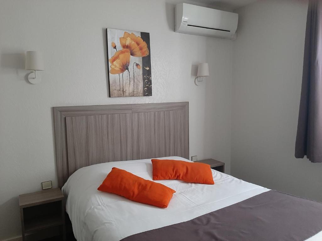 a bedroom with a bed with two orange pillows on it at Aurea Hotel in Saintes