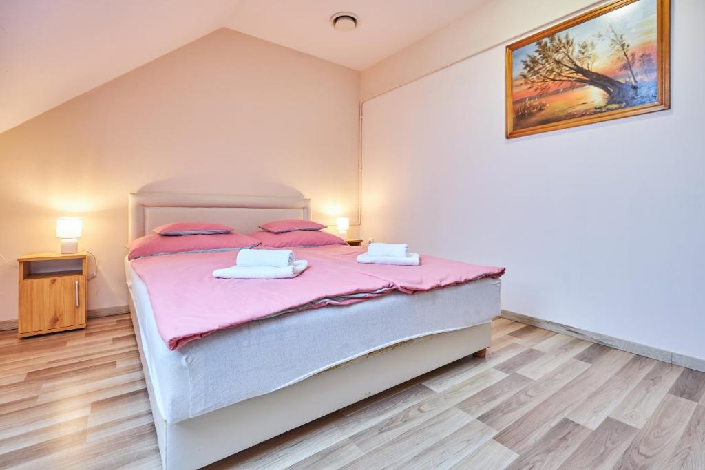 1 dormitorio con 1 cama grande con sábanas rosas en ADA Apartmanház en Hajdúszoboszló