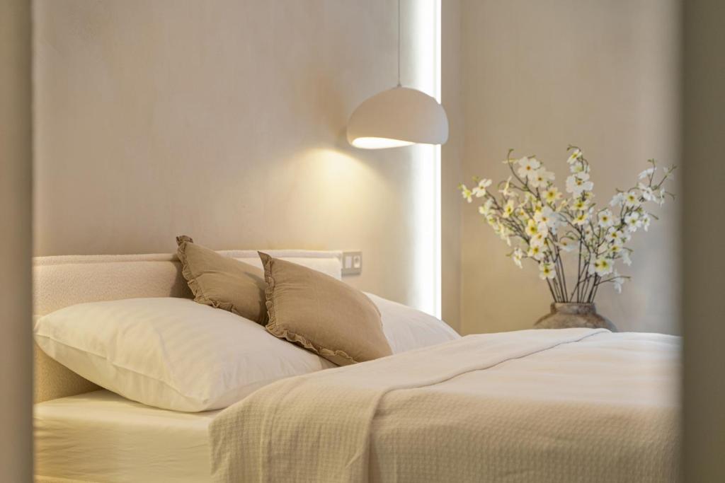 a bedroom with a white bed with a vase of flowers at Church Lane Residences in Český Krumlov