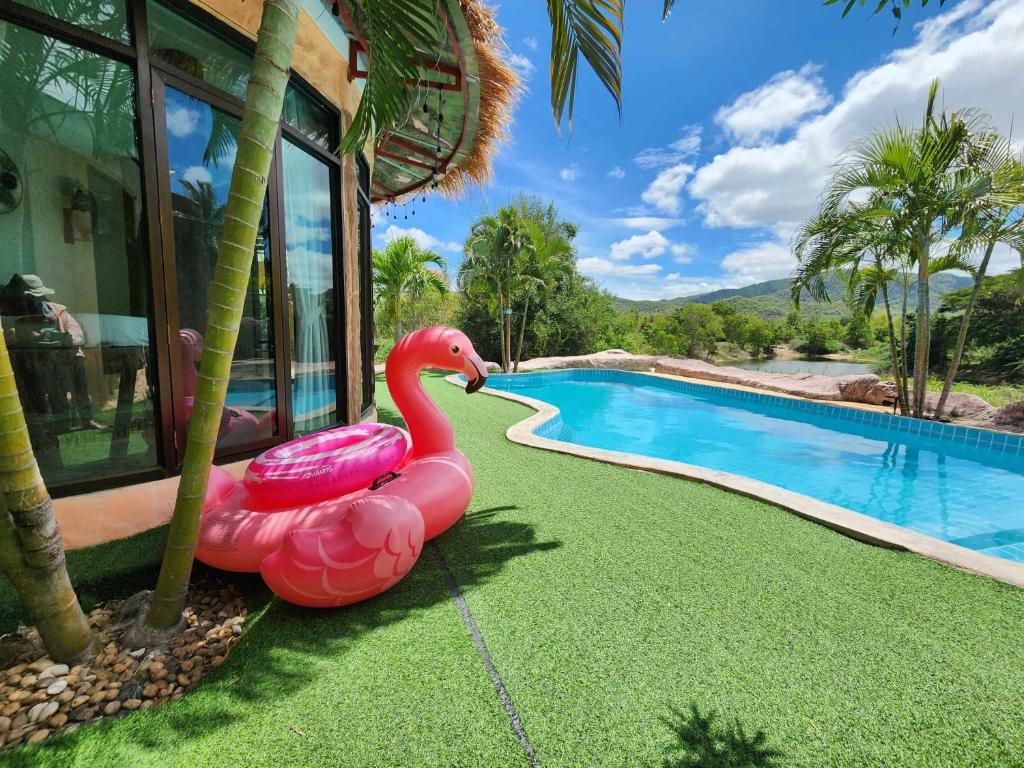 un flamant rose gonflable assis à côté d'une piscine dans l'établissement ฺBuena Vista Pool Villa Hua Hin (บ้านพักหัวหิน), à Hua Hin