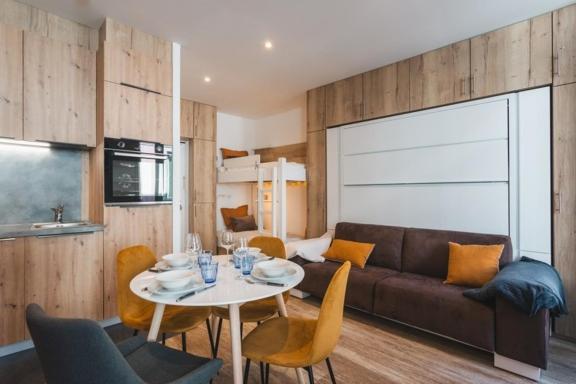 un salon avec un canapé et une table avec des chaises dans l'établissement Studio Familial Entièrement Rénové Cauterets Centre, à Cauterets