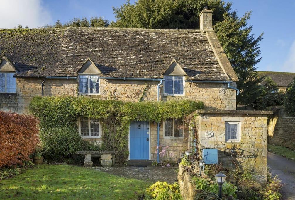 uma velha casa de pedra com uma porta azul em Slatters Cottage - 17th Century Cotswolds Cottage em Bourton on the Hill