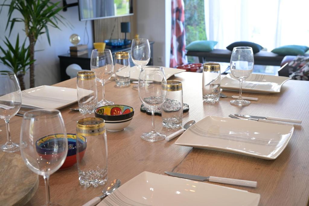 a wooden table with wine glasses on top of it at La Tanière de la baie - Maison 6-8 pers in Le Val-Saint-Père
