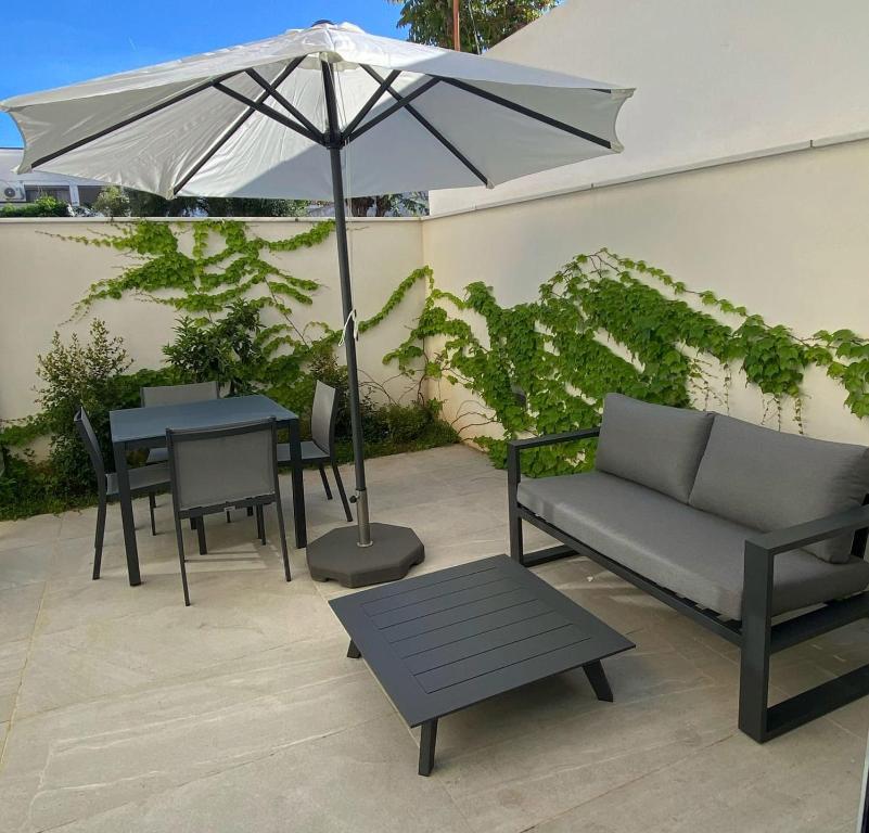 eine Terrasse mit einem Sofa, einem Sonnenschirm und einem Tisch in der Unterkunft El Naranjito de Triana in Sevilla