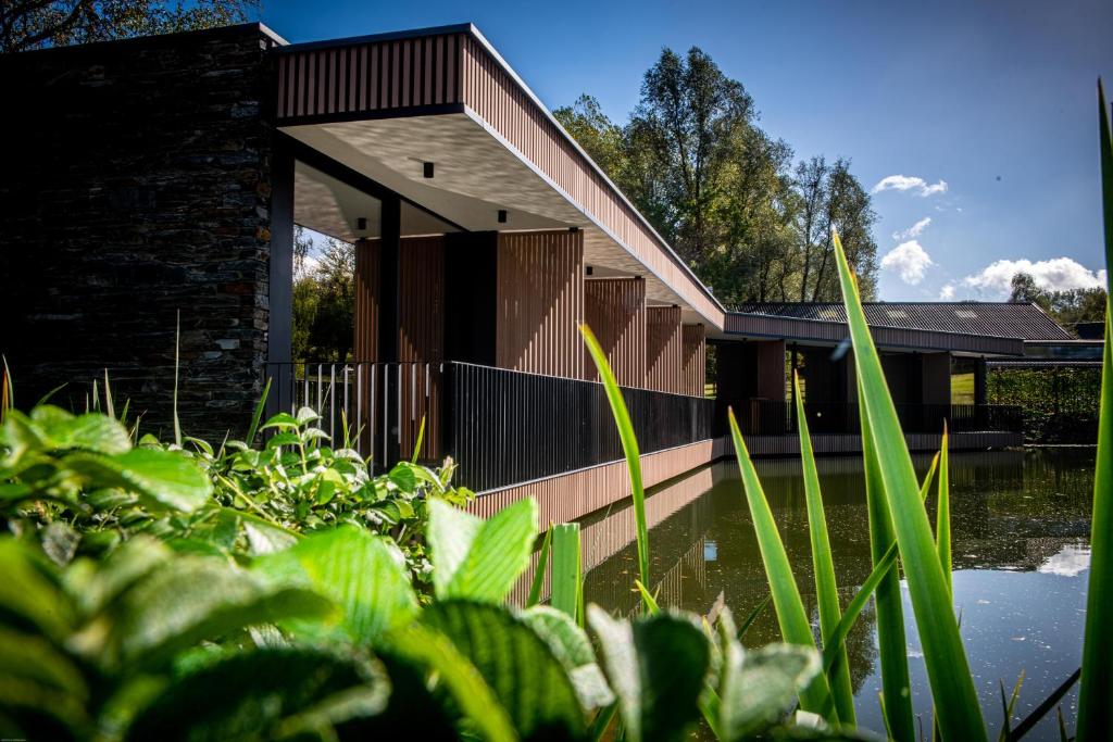 uma casa com um lago em frente em Aux Etangs - Hôtel em Battice