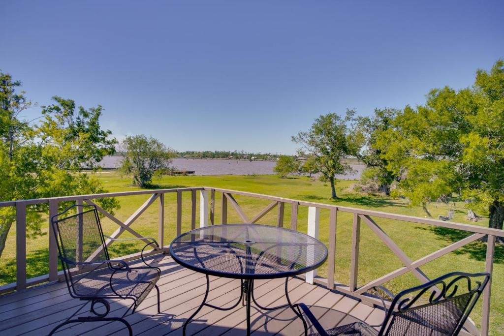 a table and chairs on a deck with a view of a field at Exquisite Lake Charles Gem - Waterfront Views in Lake Charles