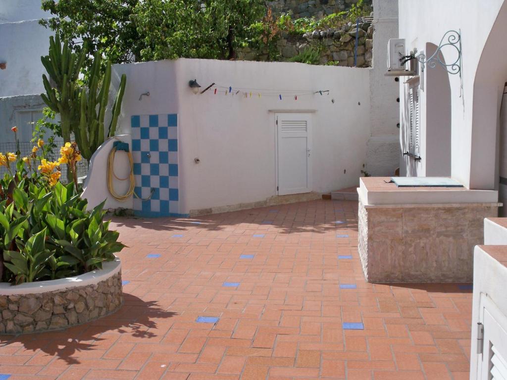 a courtyard with a gate and flowers and a brick sidewalk at L'Isolana Case Vacanza Alloro 2 in Ponza