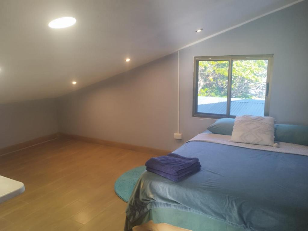 um quarto com uma cama azul e uma janela em The Yellow House Boquete (hostal) em Alto Boquete