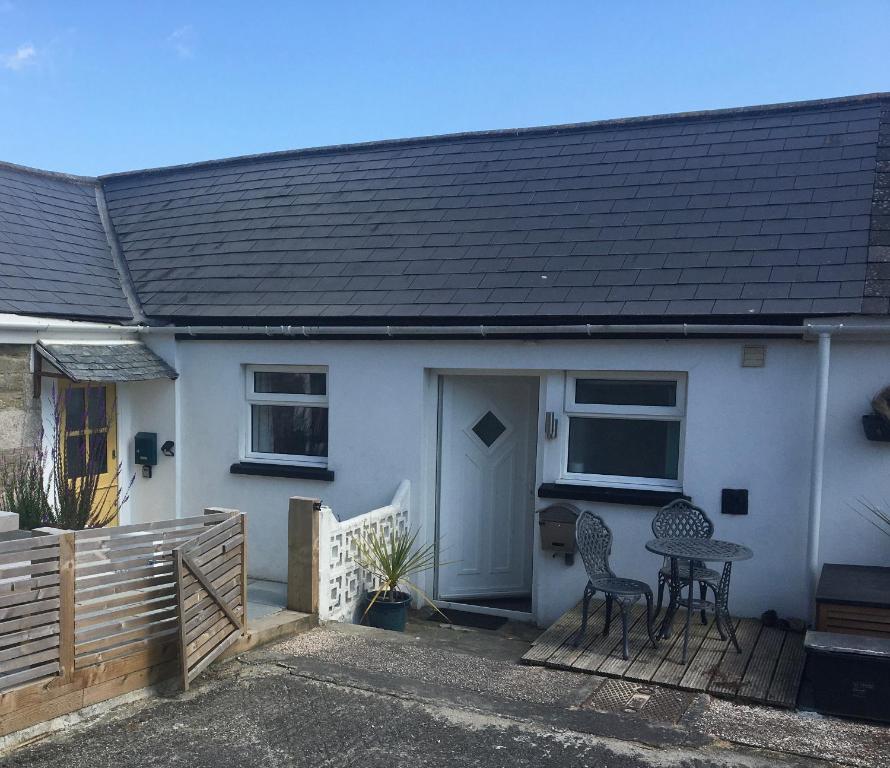 Casa blanca con porche con mesa y sillas en Cosy Cornish cottage with rural views, en Newquay