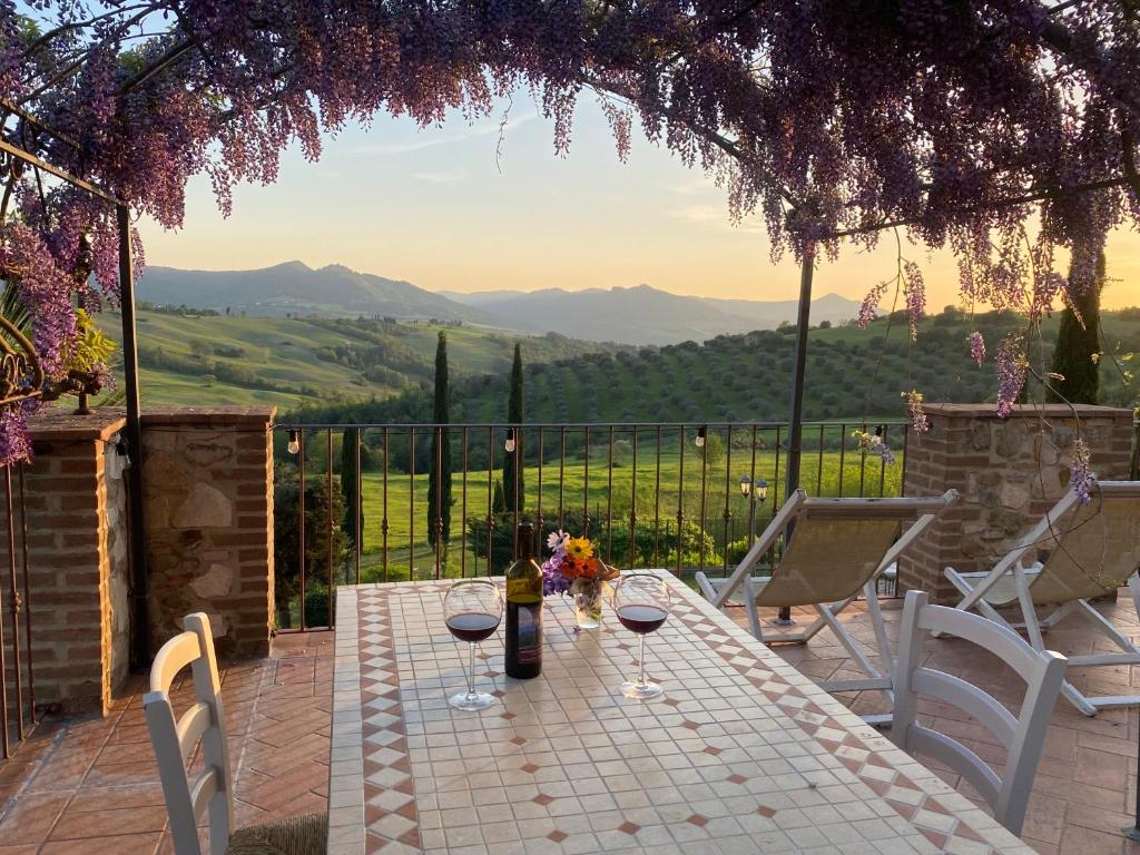 einen Tisch mit Weingläsern auf einer Terrasse mit Aussicht in der Unterkunft Agriturismo San Tommaso in Pomarance