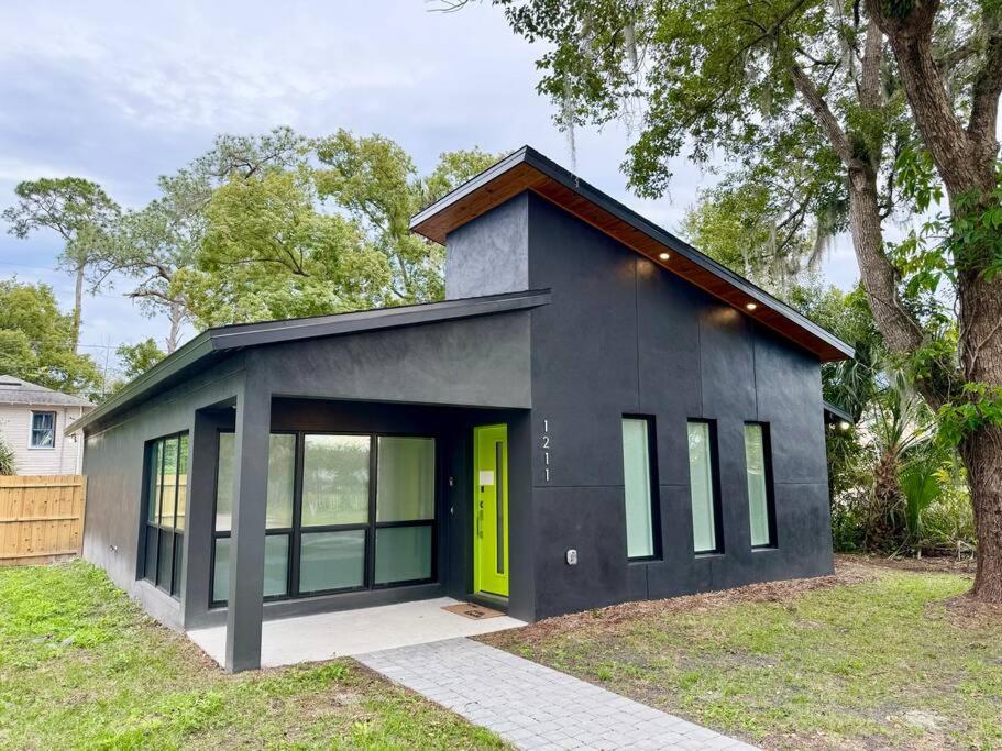 a small black house with a yellow door at The Butterfly House - with sauna in Sanford